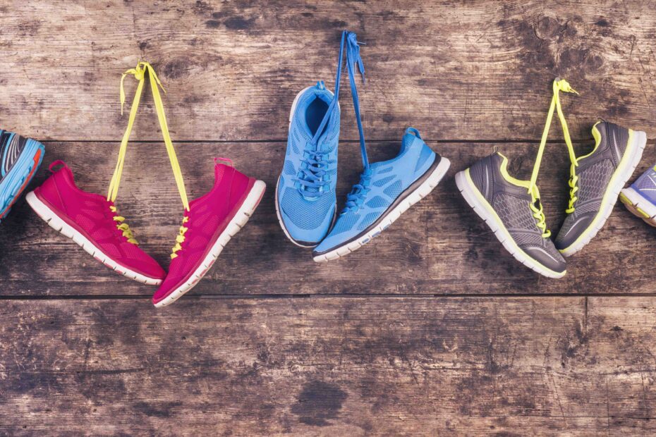 Different running shoes hanging on a wooden background.